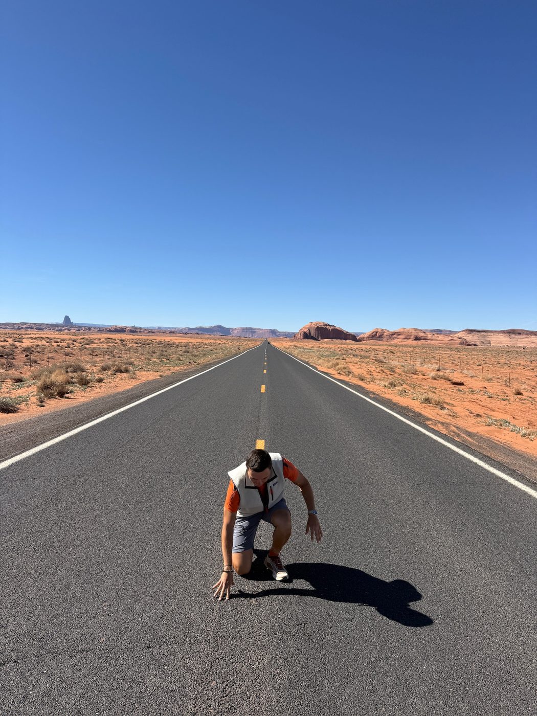 Crouching on an empty desert road in Monument Valley